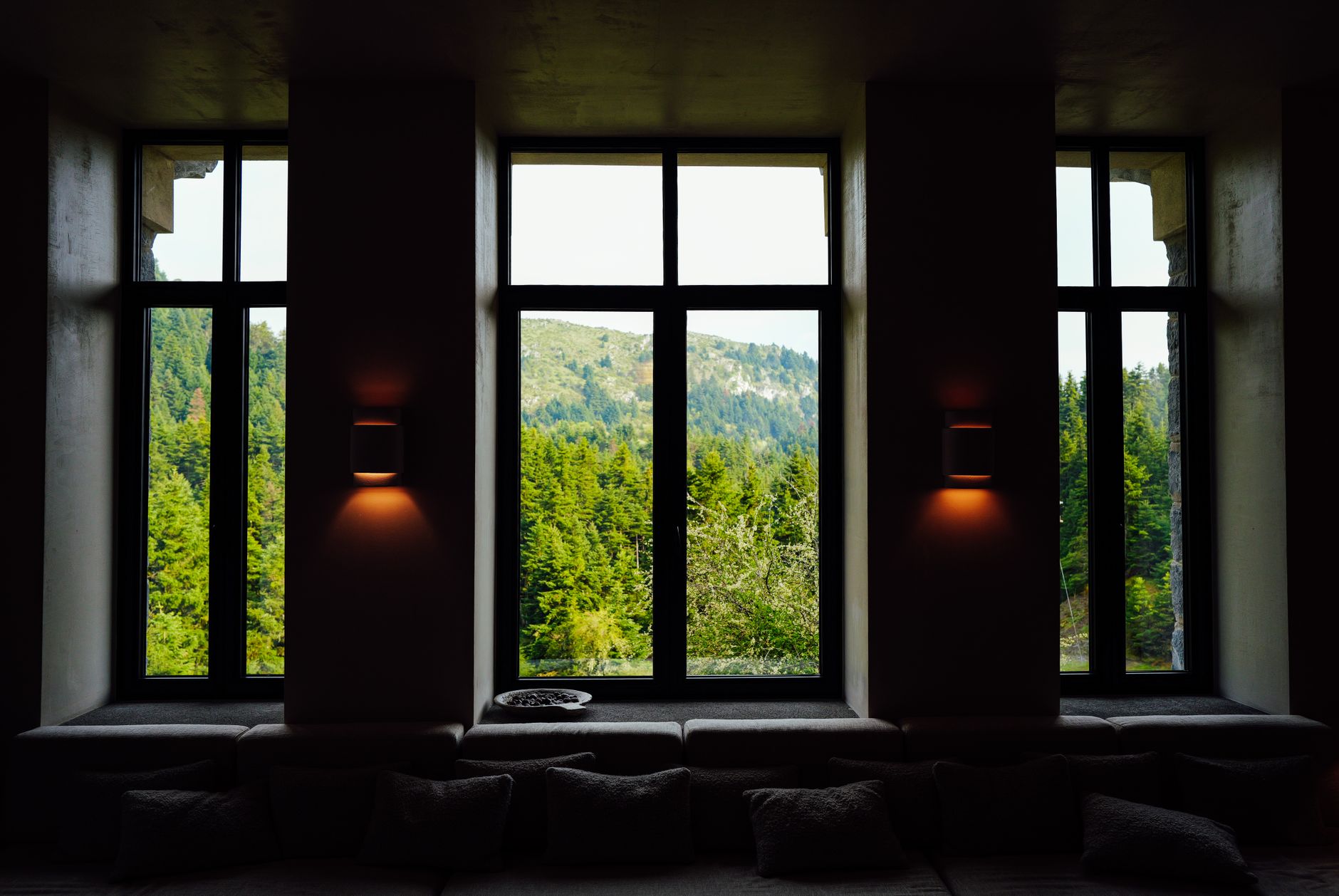 Serene forest and mountain view framed by large windows in a cozy interior setting